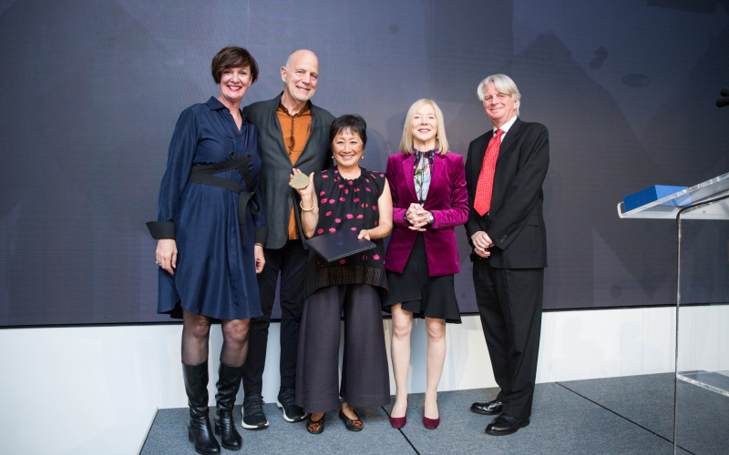 five people standing against grey backdrop