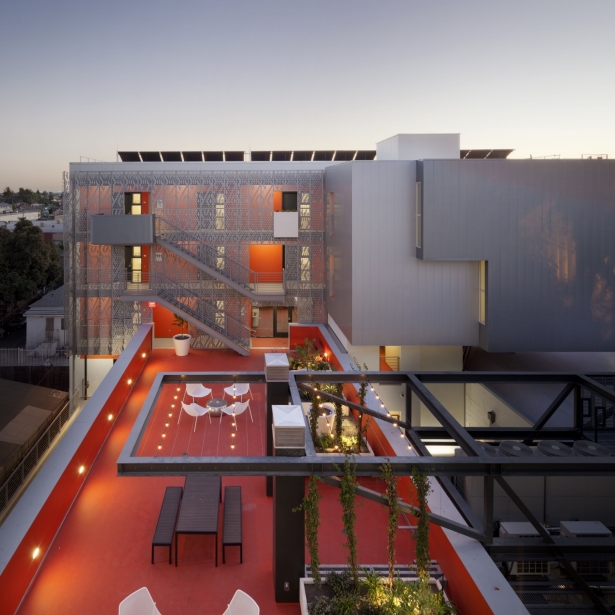 An aerial view of a modern apartment complex with an orange roof deck.
